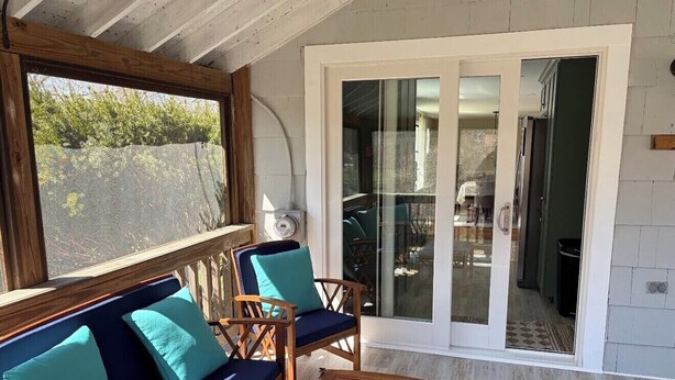 Ein überdachter Außenbereich mit Holzmöbeln und einer Glastür zum Patio.