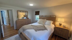 Ein Schlafzimmer mit einem Bett, Nachttischen, einem Spiegel und einem Fenster.