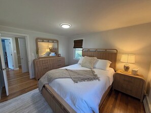 Ein Schlafzimmer mit einem Bett, Nachttischen, einem Spiegel und einem Fenster.