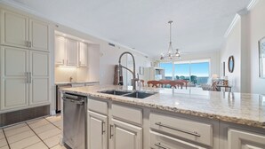 Een moderne keuken met witte kasten, een RVS vaatwasser en een granieten aanrecht.