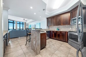 Una cocina moderna con armarios de madera oscura, salpicadero de azulejos y electrodomésticos de acero inoxidable.