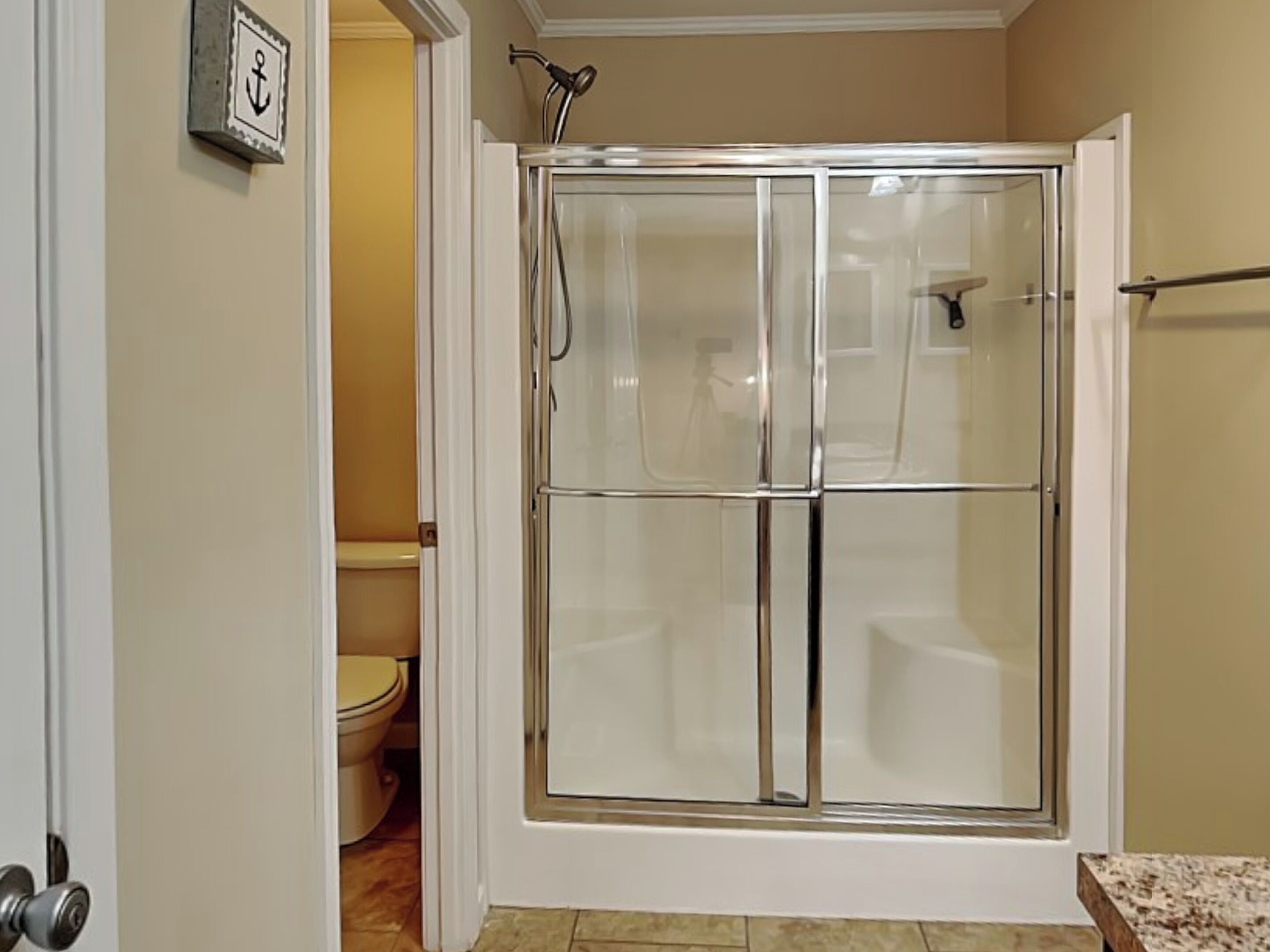 A bathroom with a glass-enclosed shower, a toilet, and a sink.