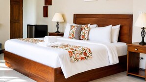 Un lit bien fait, avec une couvre-lit à motifs floraux, une tête de lit en bois et des lampes de chevet.