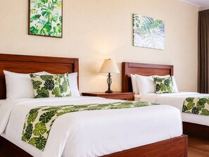 A hotel room with two beds, a nightstand with a lamp, and two wall-mounted paintings. - Aparta hotel puerta del cielo  (Quepos)