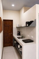 Cocina compacta con puerta de madera, cafetera, hervidor, pileta y cocina integrada por inducción.