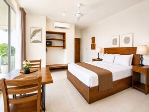 A hotel room with a bed, bedside tables, a desk with a chair, a ceiling fan, and a window with curtains. - Aparta hotel puerta del cielo  (Quepos)