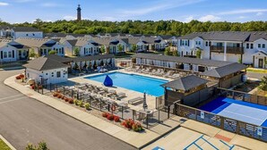 Zona residencial con casas, una piscina y un faro al fondo.