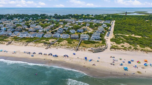 Vista aérea de una zona residencial costera con casas, una playa y un muelle.