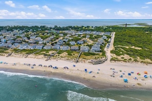 An aerial view of a coastal residential area with houses, a beach, and a pier. - Swell | Walk to the Beach | Hot Tub, Dog Friendly, and Community Pool (Corolla)