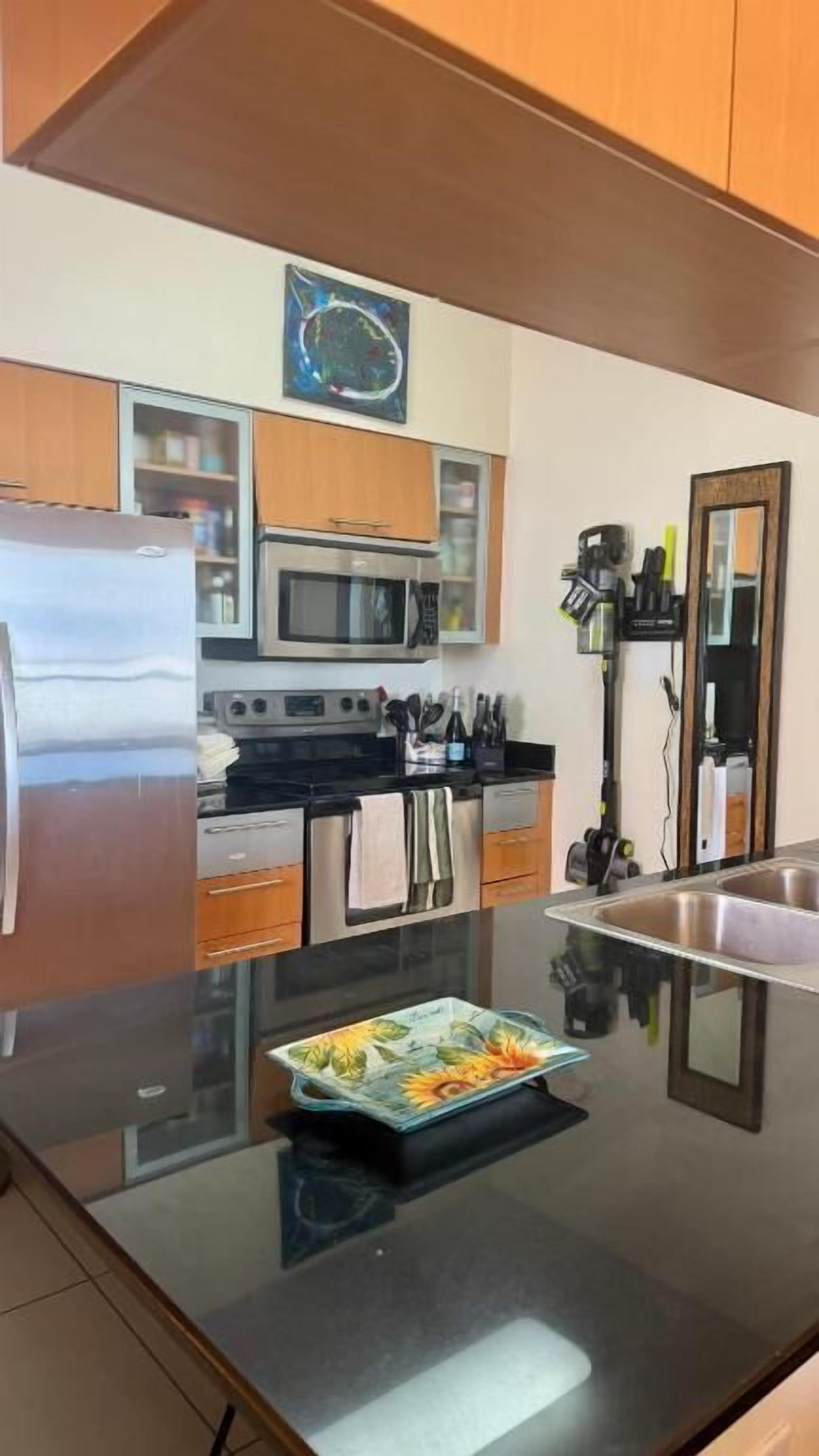 A modern kitchen with stainless steel appliances, wooden cabinets, and a black countertop.