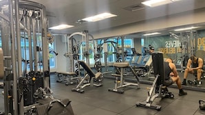 A gym with various exercise machines, mirrors, and a bench. - Urban One Retreat (Miami)