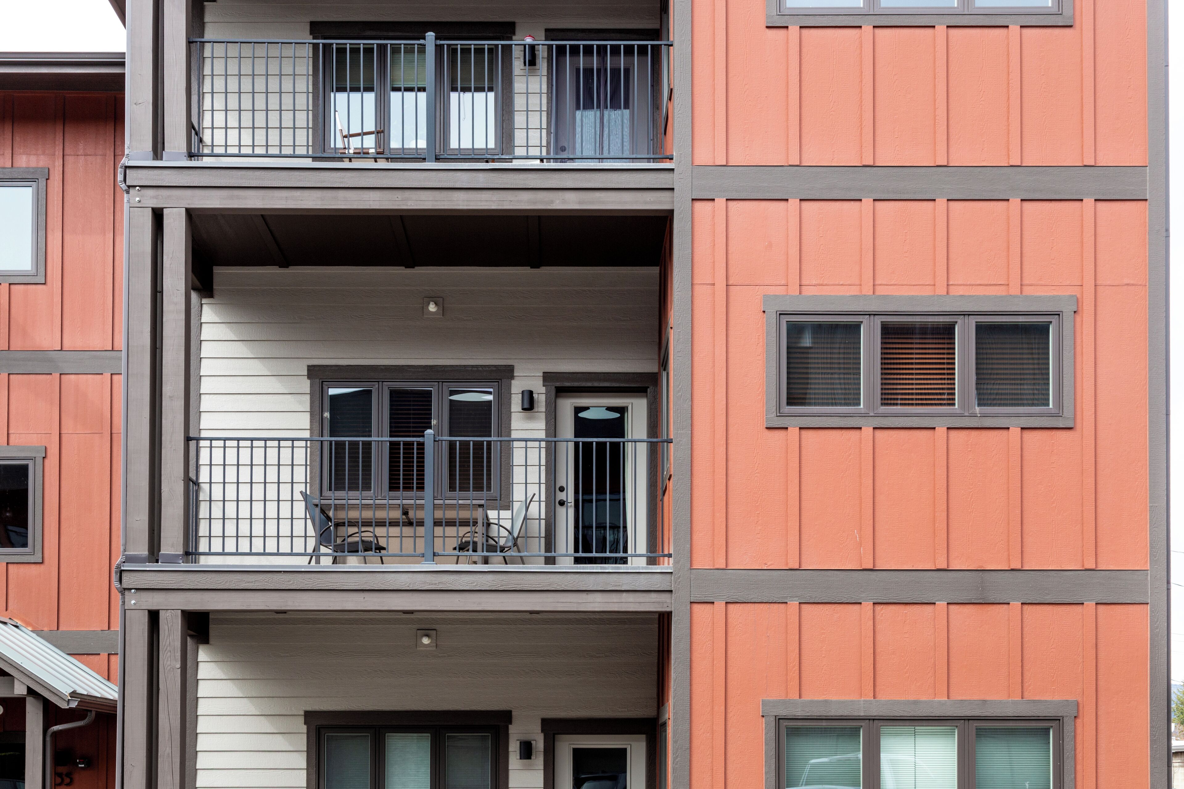Een meerhoog gebouw met balkons, ramen en een deur.