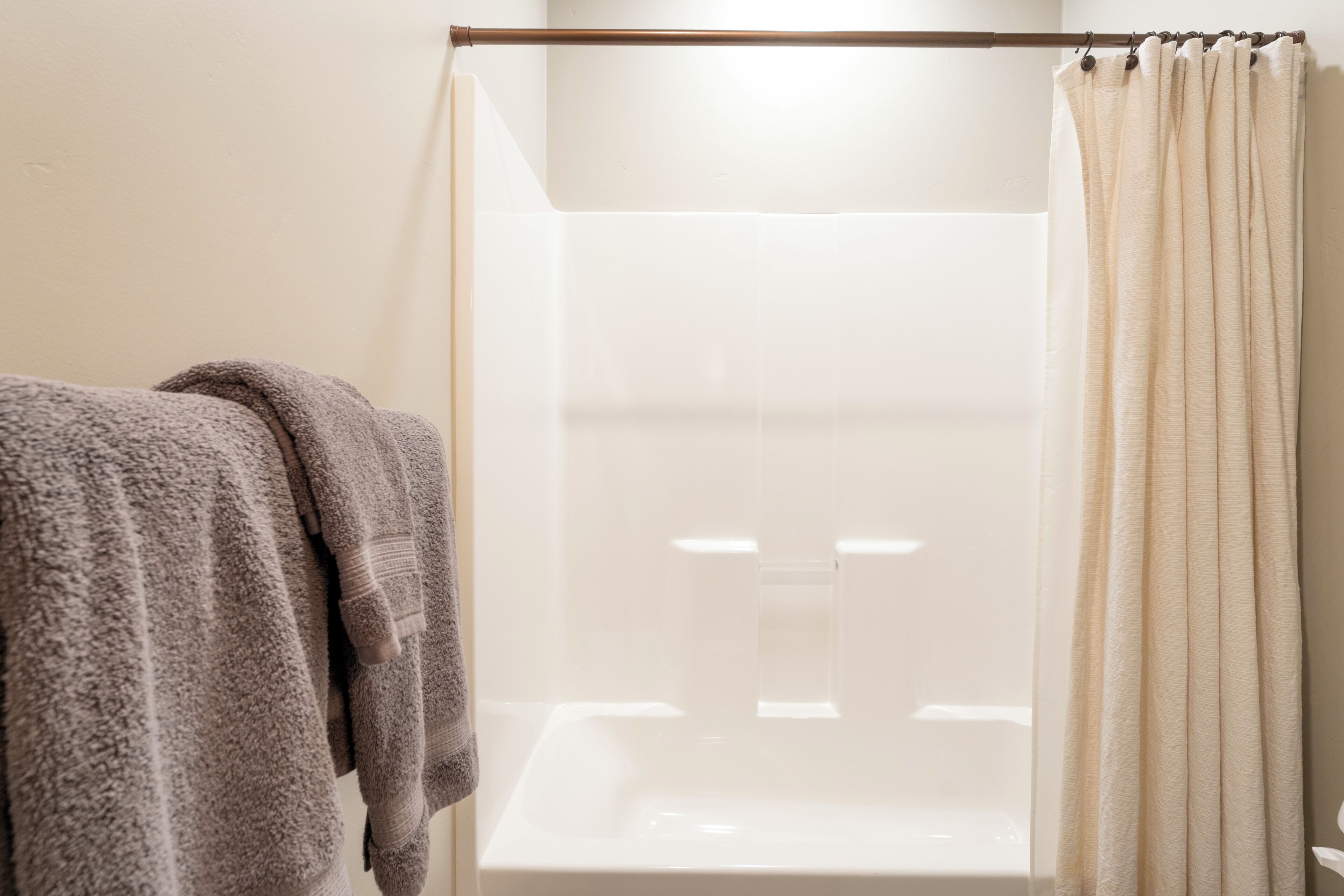 A bathroom with a shower curtain, a towel, and a bathtub.
