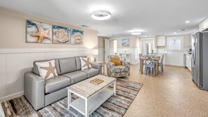 Un salon avec un canapé gris, une table basse et un coin repas comprenant une table et des chaises.