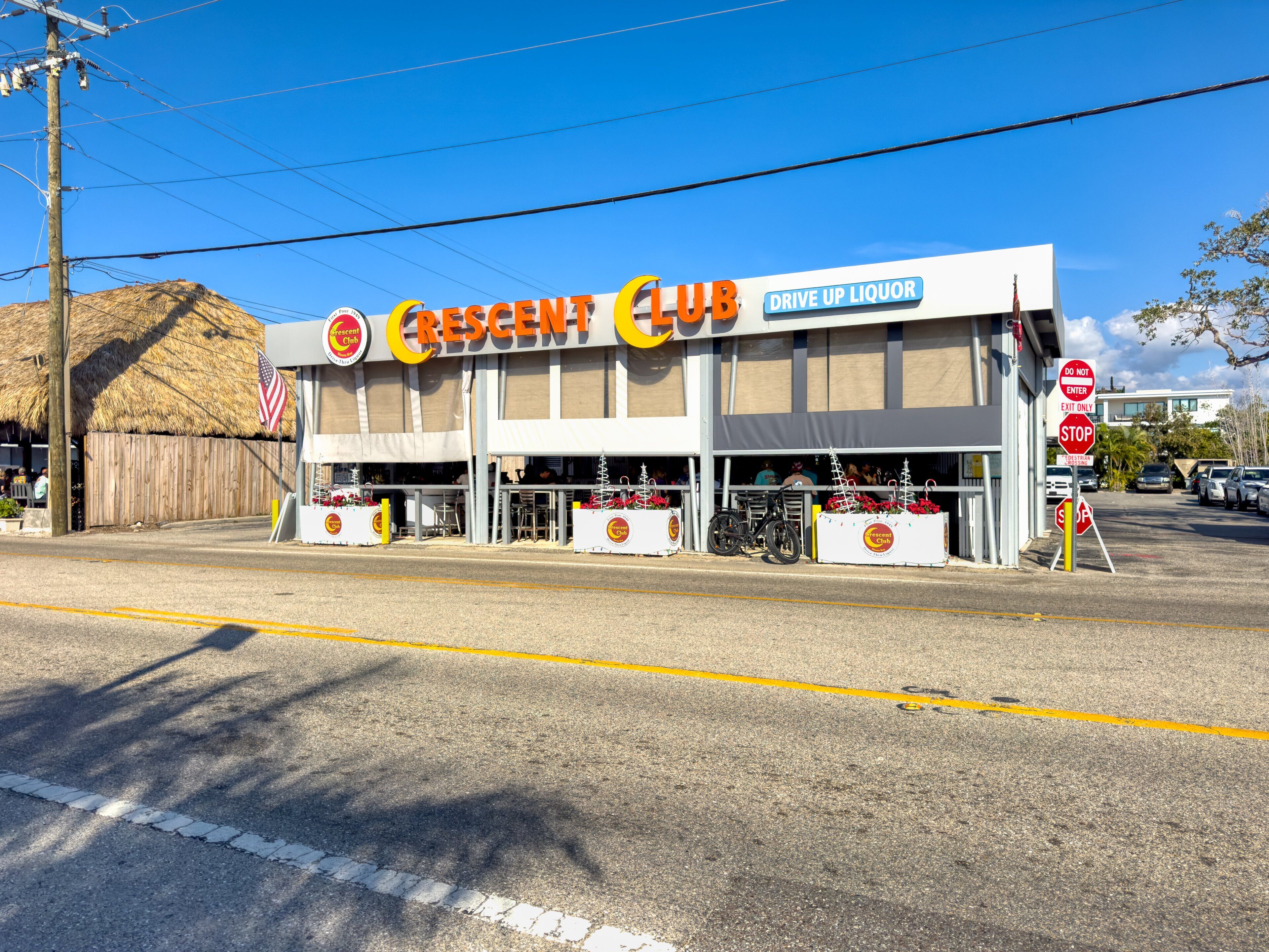 A Crescent Club building with a drive-up liquor service, a wooden fence, and a stop sign.