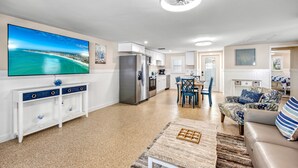 Un salon moderne doté d’un téléviseur à écran plat, d’un coin repas, d’une cuisine et d’un espace salon confortable avec un canapé et des fauteuils.