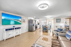 A modern living room with a flat-screen TV, a dining area, kitchen, and a cozy seating area with a sofa and chairs. - Key Life Sands | Duplex Unit Near Crescent Beach with Private Outdoor Living (Sarasota)