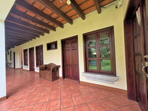 A corridor with tiled flooring, wooden doors, and a bench. - Alana Hotel (Antigua Guatemala)