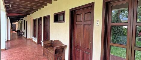 A corridor with tiled flooring, wooden doors, and a bench.
