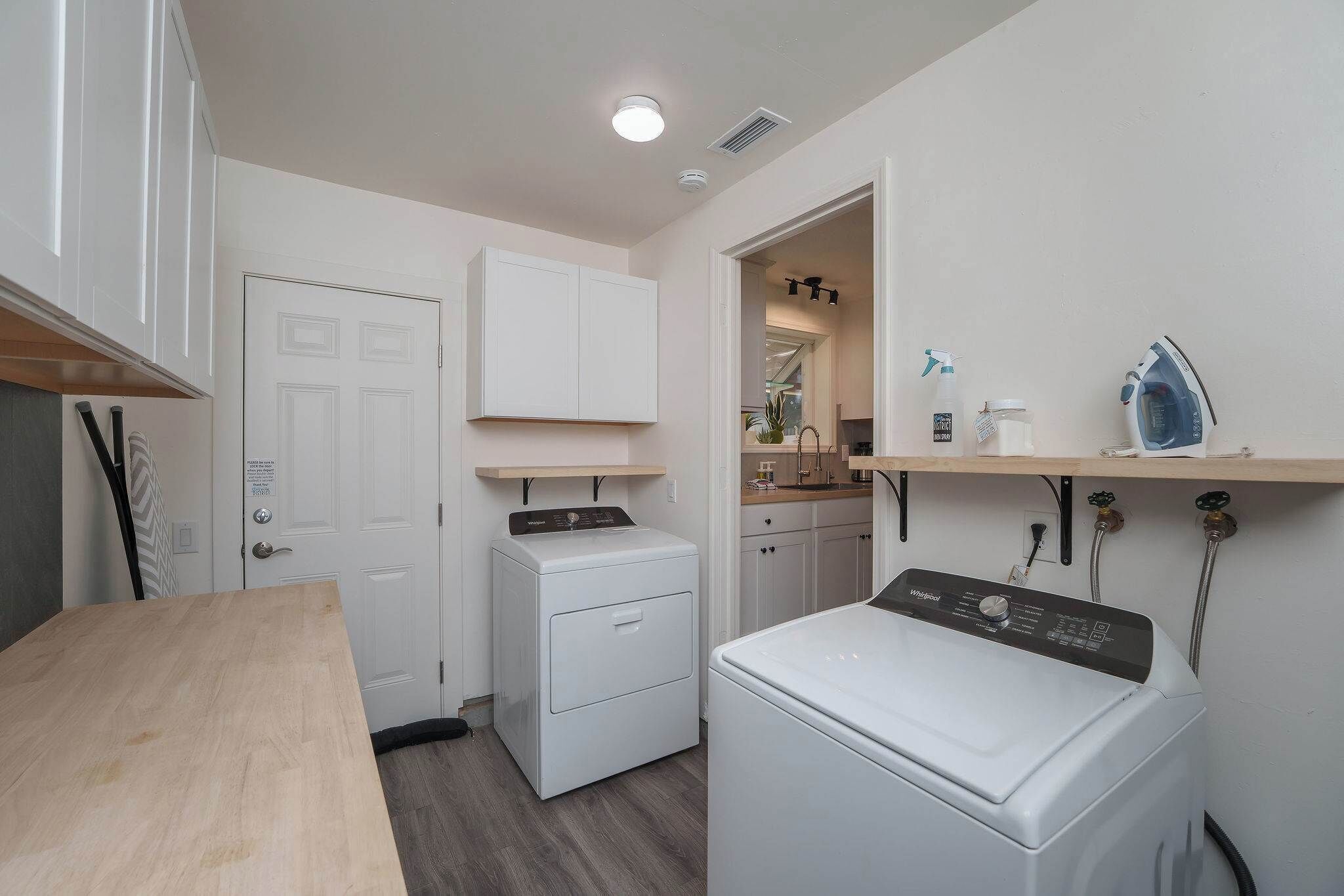 A laundry room with a washing machine, dryer, and ironing station.