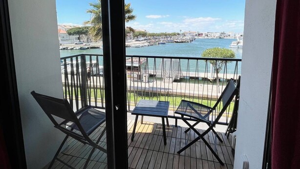 Een balkon met uitzicht op een jachthaven en stadsbeeld.