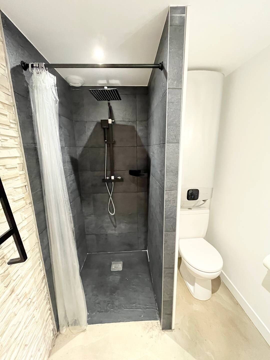 A modern bathroom with a shower, toilet, and a small sink.