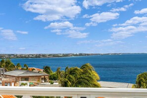 A coastal view with a clear sky, a body of water, and a distant shoreline with buildings. - Caribbean Club 111 Parrots Perch on a small-scale resort with beautiful views (Kralendijk)
