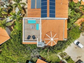 An aerial view of a house with a wooden deck, a pool, and a large umbrella. - Caribbean Club 111 Parrots Perch on a small-scale resort with beautiful views (Kralendijk)