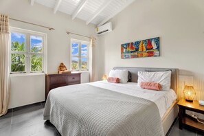 Une chambre d’hôtel comprenant un lit, une table de chevet, une fenêtre avec des rideaux, un tableau et un appareil de climatisation.
