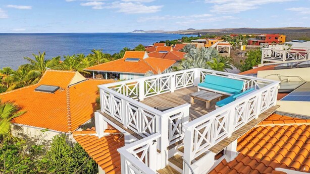 Un complexe hôtelier doté d’une piscine, d’une terrasse en bois et offrant une vue sur l’océan.