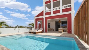 Uma casa de dois andares com piscina, varanda e área de pátio.