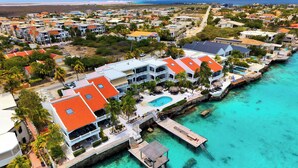 A coastal resort with multiple buildings, a swimming pool, and a pier extending into turquoise waters. - Apartment Belmar 6 with a beautiful view and refreshing shared pool (Kralendijk)