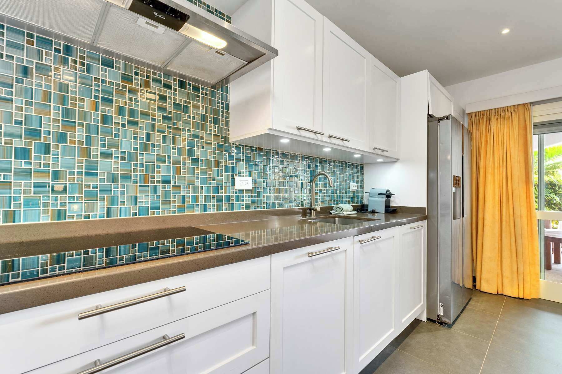 A modern kitchen with white cabinets, a tiled backsplash, and a stainless steel refrigerator.
