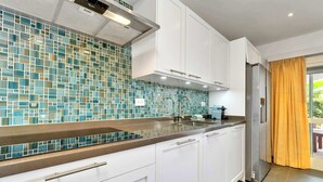 A modern kitchen with white cabinets, a tiled backsplash, and a stainless steel refrigerator. - Apartment Belmar 6 with a beautiful view and refreshing shared pool (Kralendijk)
