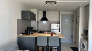 Eine kleine Küche mit Kaffeemaschine, Mikrowelle und Waschmaschine.
