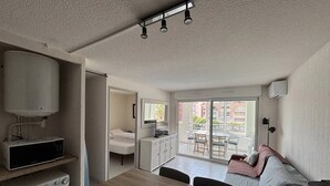 Ein kompakter Wohnbereich mit Küchenzeile, Essbereich, Sofa und einem Balkon mit Blick.
