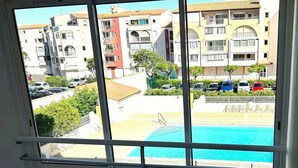 Ein Zimmer mit großem Fenster mit Blick auf einen Swimmingpool und einen Parkplatz.