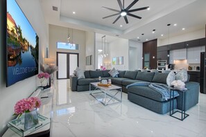 A modern living room with a sofa, coffee table, and a TV displaying a scenic view. - VILLA CORAL GLOW – HEATED POOL | WATER VIEW | BOAT RENTAL + TOURS VOUCHER INCL. (Cape Coral)