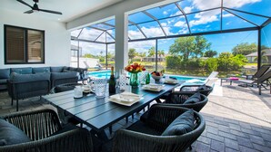 Un espace de vie intérieur/extérieur doté d’une piscine, de sièges et d’un ventilateur de plafond.