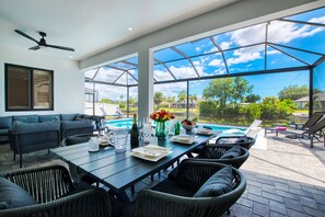 An indoor/outdoor living area with a pool, seating, and a ceiling fan. - VILLA CORAL GLOW – HEATED POOL | WATER VIEW | BOAT RENTAL + TOURS VOUCHER INCL. (Cape Coral)