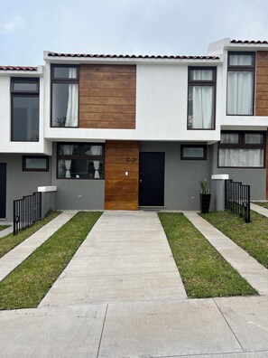 Un immeuble résidentiel moderne à deux étages, doté d’une entrée centrale, d’un élément décoratif en bois et du numéro « 1C-29 » sur la porte.