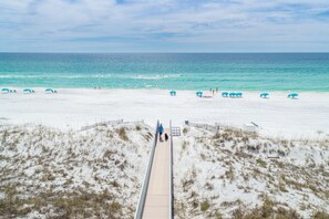 A beach with a wooden boardwalk leading to the water, sandy dunes, and beach umbrellas. - Casa Del Mare Caribe (Miramar Beach)