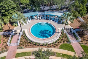 An aerial view of a resort with a central circular pool, surrounded by lounge chairs and palm trees. - Casa Del Mare Caribe (Miramar Beach)