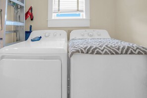 A laundry room with two washing machines, a drying rack, and a window with blinds. - Casa Del Mare Caribe (Miramar Beach)