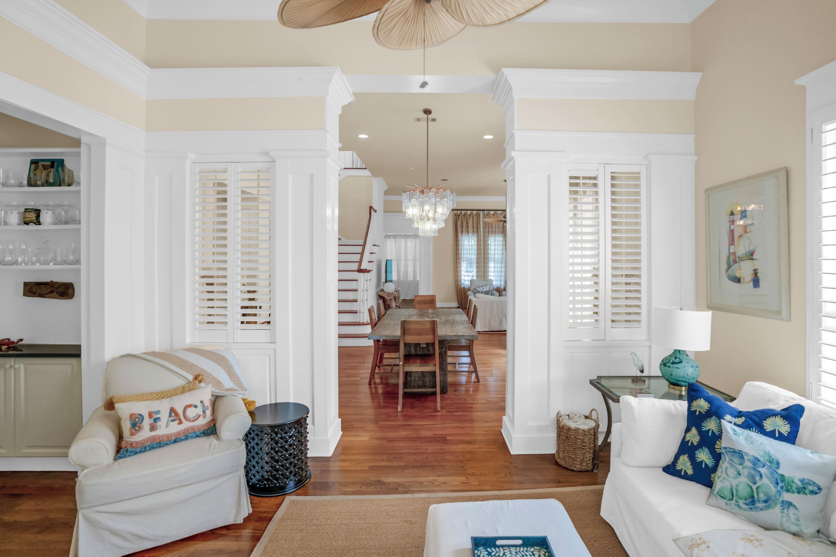 A spacious living room with a dining area, wooden flooring, and a staircase leading to another level.
