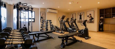 Un gimnasio con diversos equipos de ejercicio, incluyendo cintas de correr, máquinas de pesas y pesas libres.