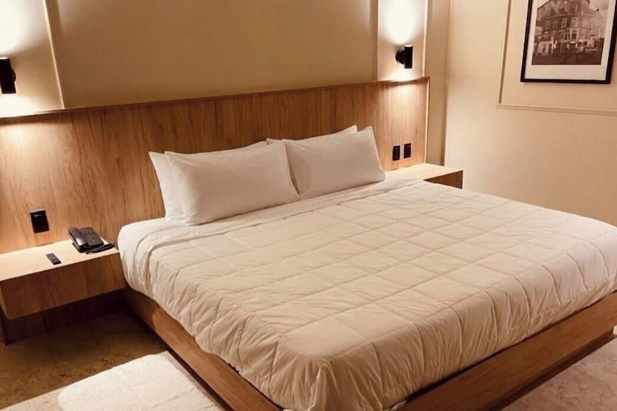 A neatly made bed with a wooden headboard, bedside tables with lamps, and a framed picture on the wall.