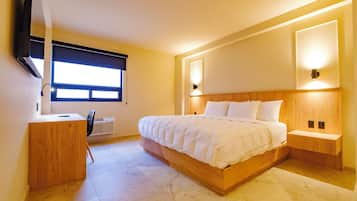 A modern bedroom with a large bed, bedside tables, a desk, and a chair.