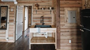 A rustic interior with wooden walls, a kitchen area, and a dining table.