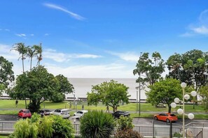 Un parking avec des voitures, des arbres et une vue sur l’océan.